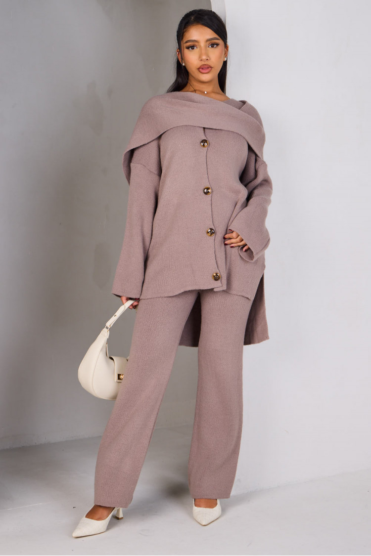 Three-piece knit co-ord set featuring a buttoned cardigan, matching trousers, and a coordinating scarf, styled with a minimalist white bag.