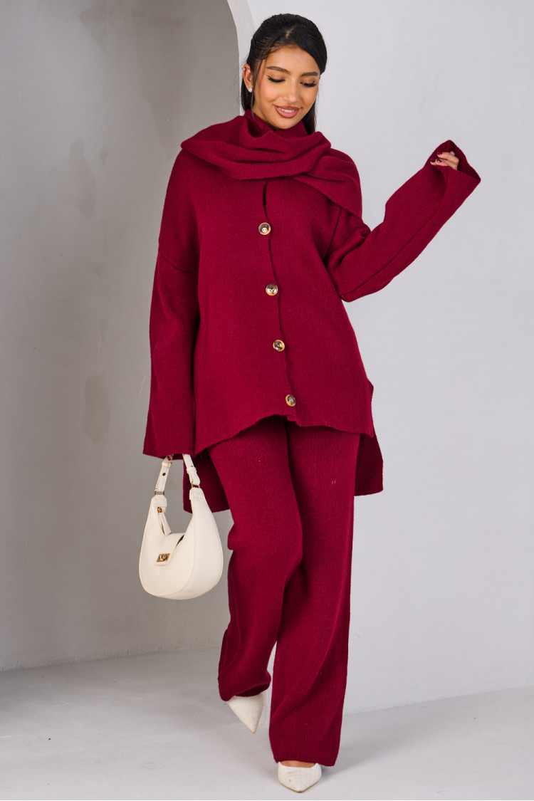 Three-piece knit co-ord set featuring a buttoned cardigan, matching trousers, and a coordinating scarf, styled with a minimalist white bag.