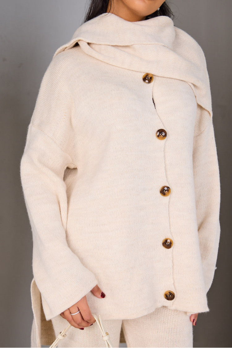 Three-piece knit co-ord set featuring a buttoned cardigan, matching trousers, and a coordinating scarf, styled with a minimalist white bag.